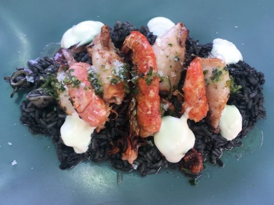 Shrimp & squid on a bed of black rice with aioli and herb garnish